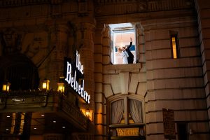 Bride and groom kiss and celebrate in an upstairs window of the Belvedere