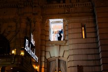 Bride and groom look excited about being married in an upstairs window