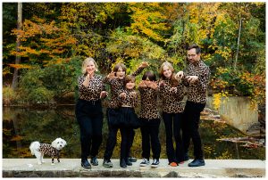 Family wearing matching outfits makes leopard rawr hand gestures at camera.