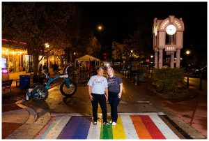 LGBTQ couple in downtown Takoma Park engagement photos stands on a rainbow walkway