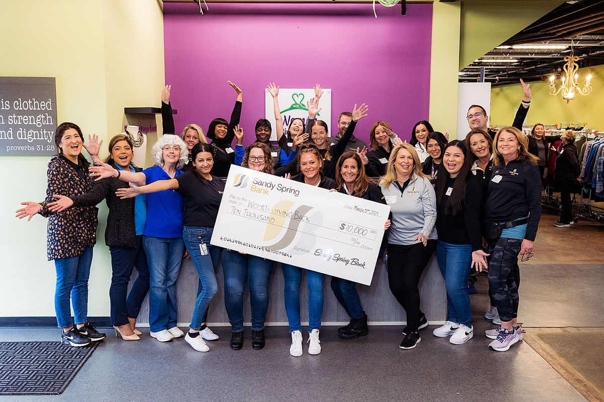 A group of Sandy Spring Bank volunteers smiles at the camera and poses with donation check for Women Giving Back.