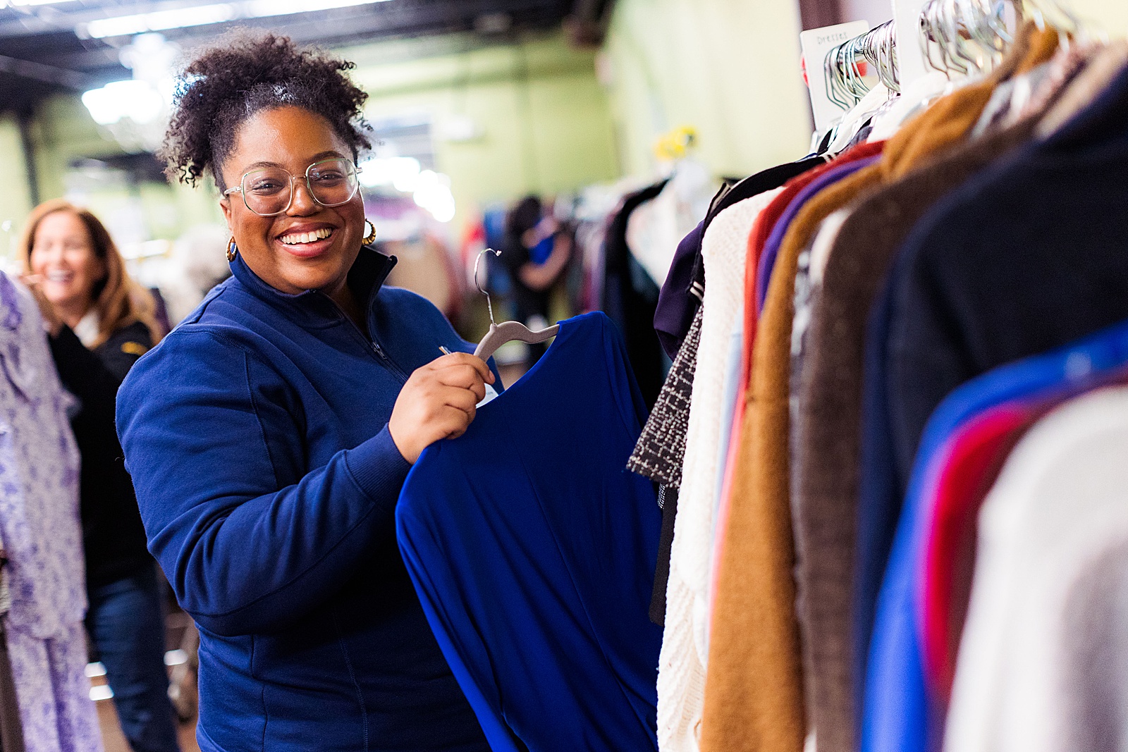 A volunteer sorts through racks of clothing during a corporate volunteer event at Women Giving Back.