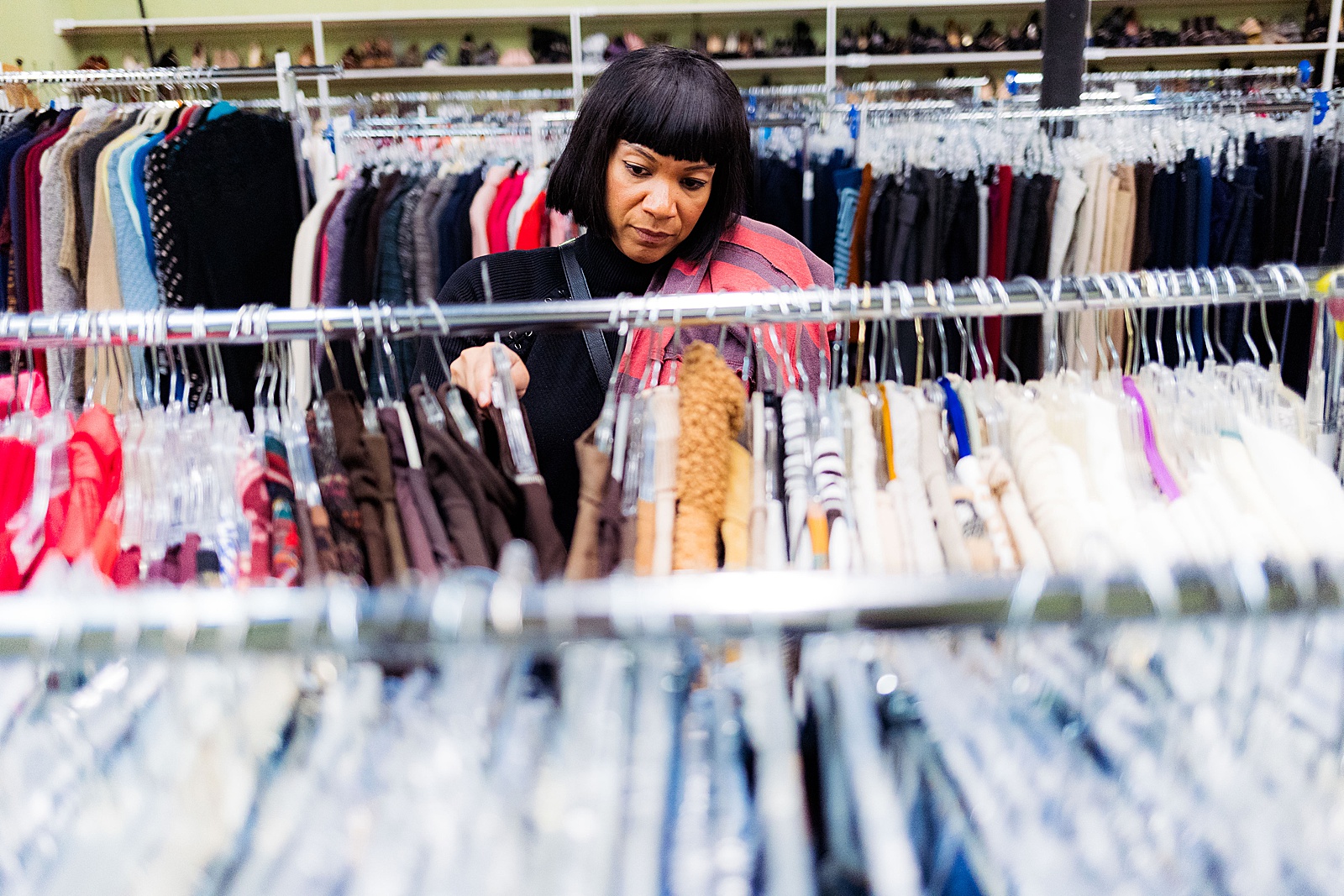 A volunteer sorts through racks of clothing during a corporate volunteer event at Women Giving Back.