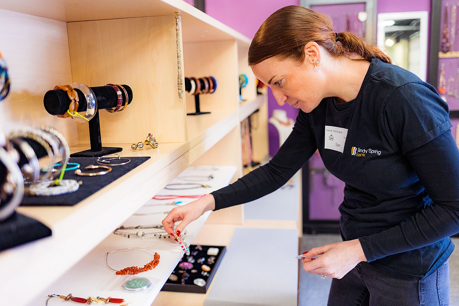 Sandy Spring Bank volunteer puts jewelry out on display during a corporate volunteer event.