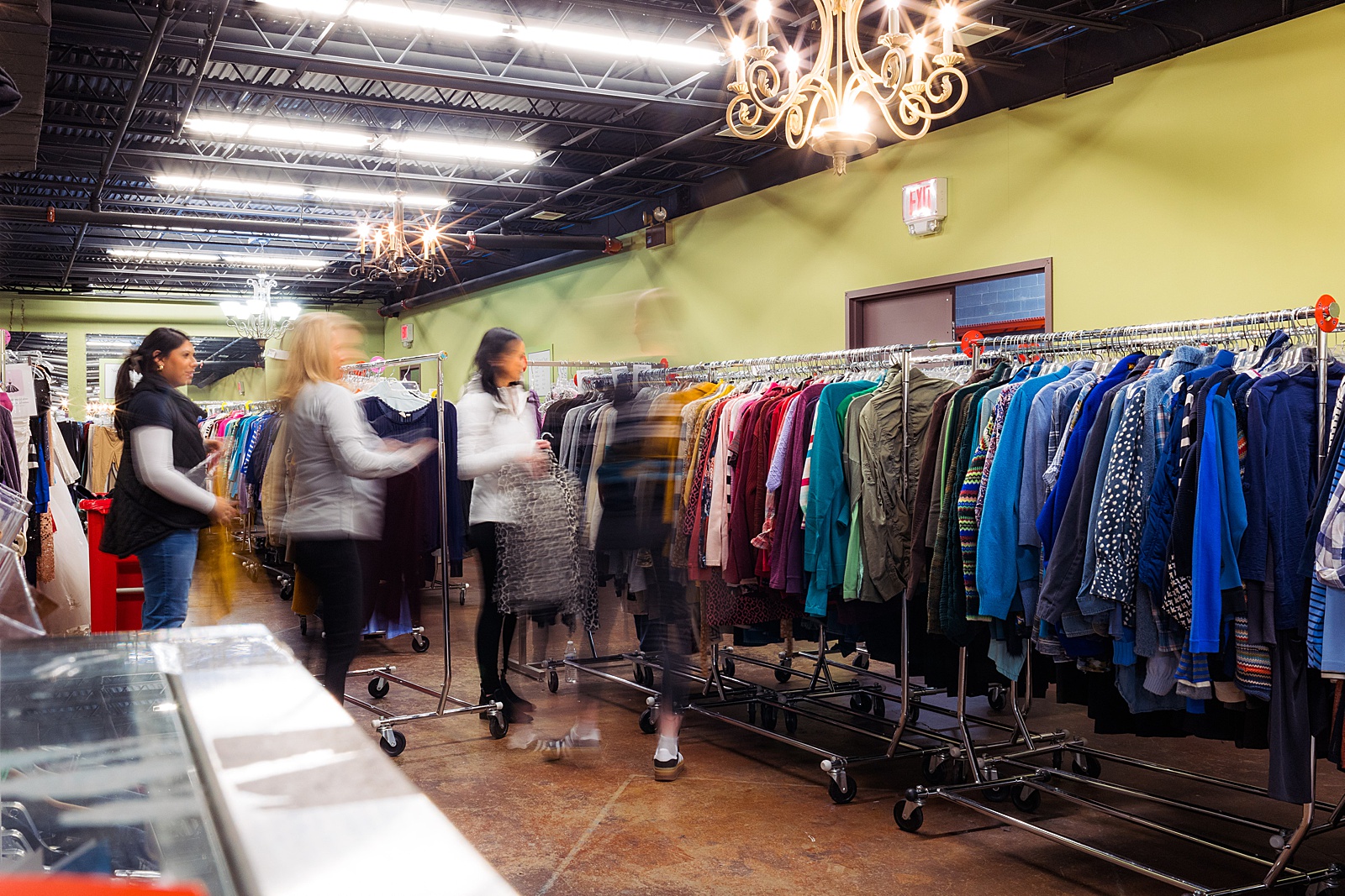 Slow motion of a corporate group of volunteers sorting clothing at Women Giving Back. 