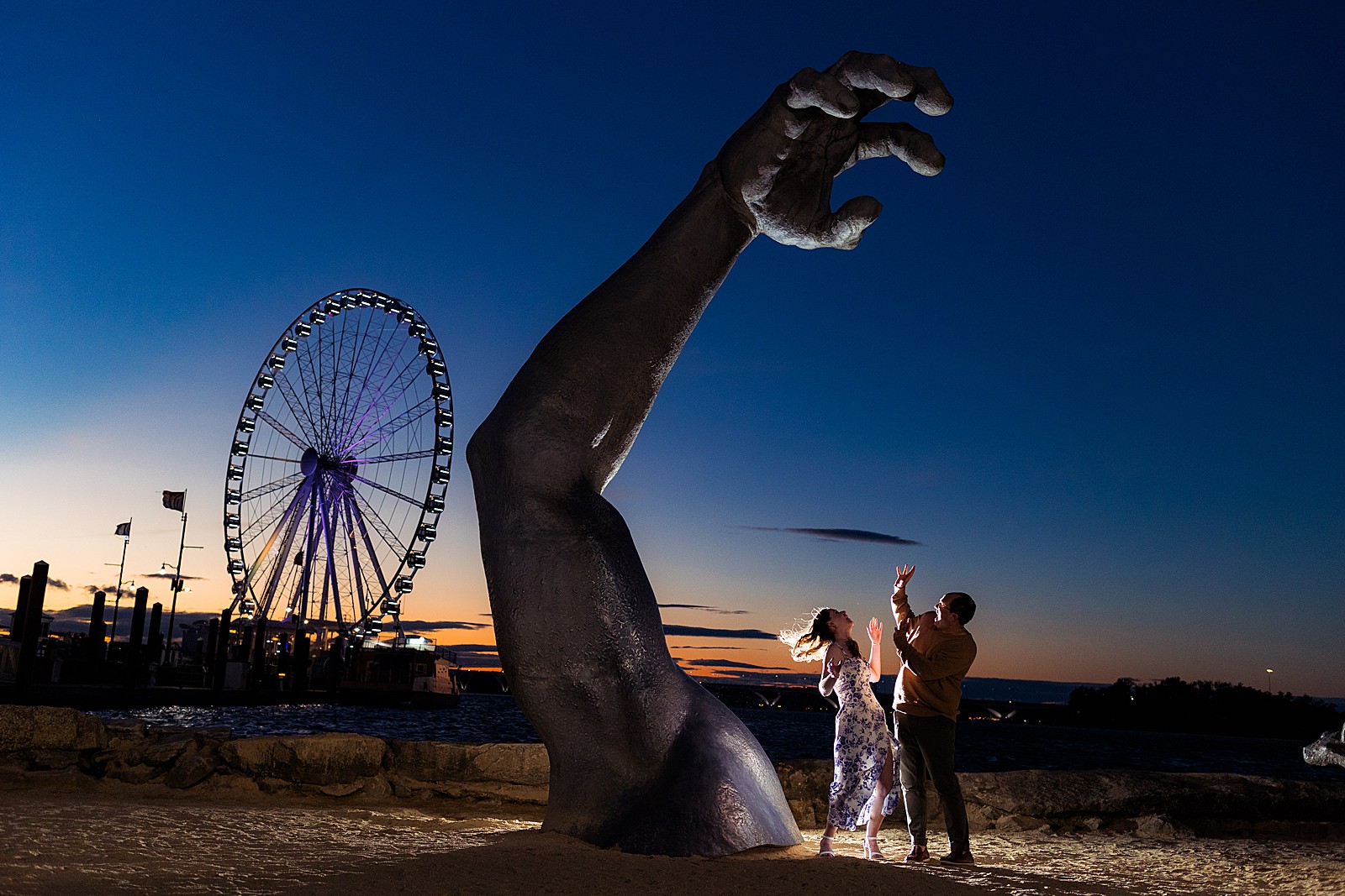 Couple pretends to be afraid of the hand coming out of the ground. 