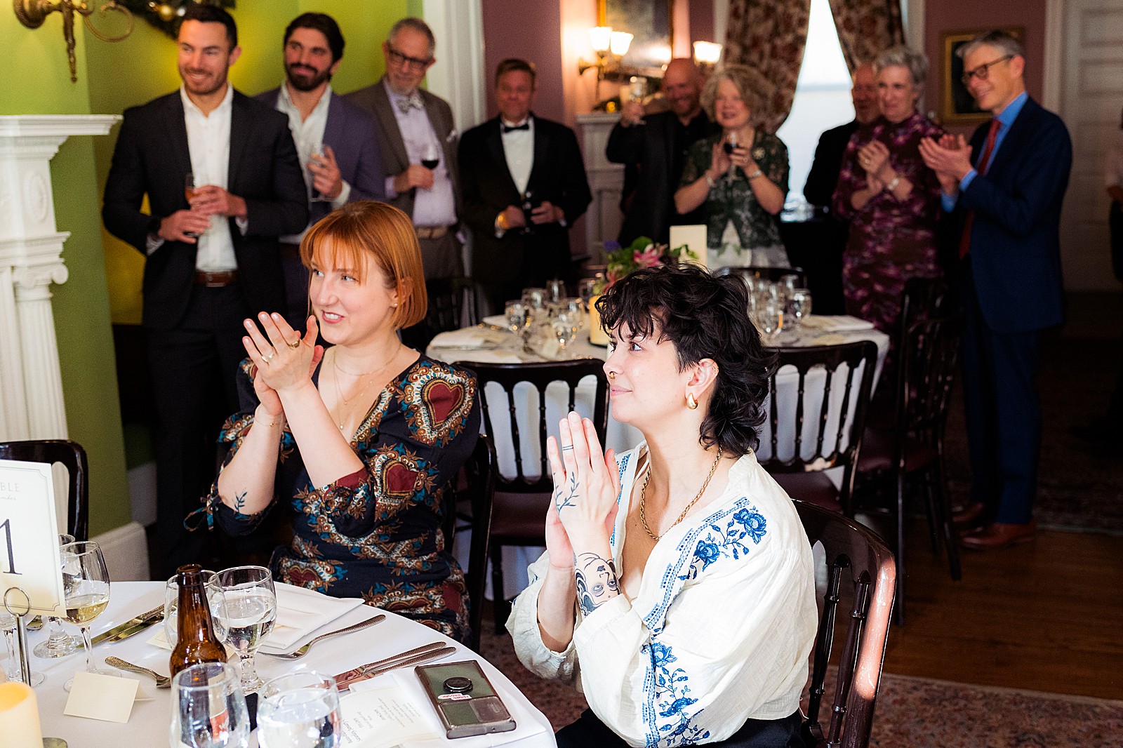 Guests at tables watch and clap for the speeches. 